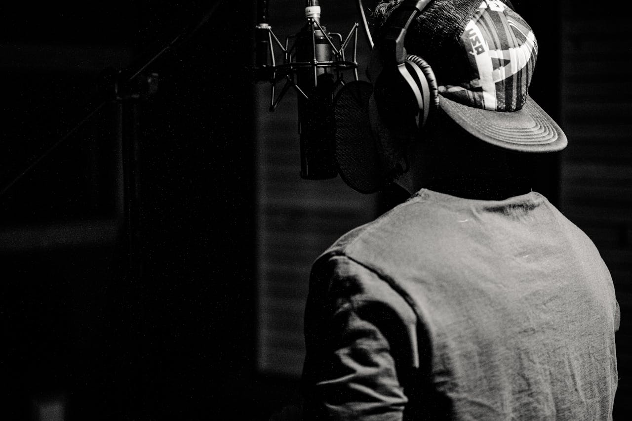 A male singer recording music in a studio, captured in a black and white style.